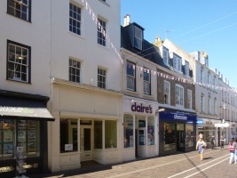 There is a marked distinction between the large department stores on the north side of King Street, and smaller properties on the south. Here we have a row of the latter, of indeterminate age, one a sorry example of many of St Helier's precinct shops without a tenant