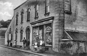 W T Le Cocq's shop in Gorey Village, now a hotel. The picture shows an unknown couple on the left, and then Sybil, Walter Thomas, Reginald, Gertrud, Edith, and Clifford Le Cocq