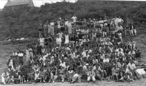 A large group of holidaymakers poses for a photograph on the beach in 1930
