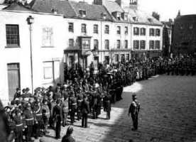 A crowd watches a military parade in 1903
