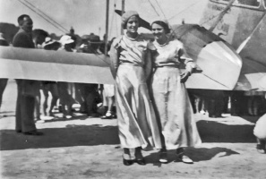 Sisters Elsie and Blanche Audrain pose in front of a biplane on the beach at West Park