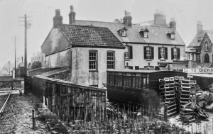 The level crossing over St Clement’s Road, looking east. The large building in the centre background is still there, although somewhat remodelled. Above the ridge can be seen the distinctive flat-bottomed chimney stack on the Normandie Hotel, and to the right of the telephone pole on the left is the roofline of the Demi des Pas Hotel