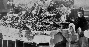 Hilda Carrel with her grandmother Elizabeth Mary Carre, nee Le Huray, at her Guernsey market fruit stall in about 1896